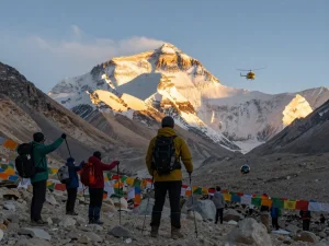 Everest Base Camp Trek with Helicopter Return, trekkers celebrating at sunset, helicopter in background, dramatic mountain scenery.